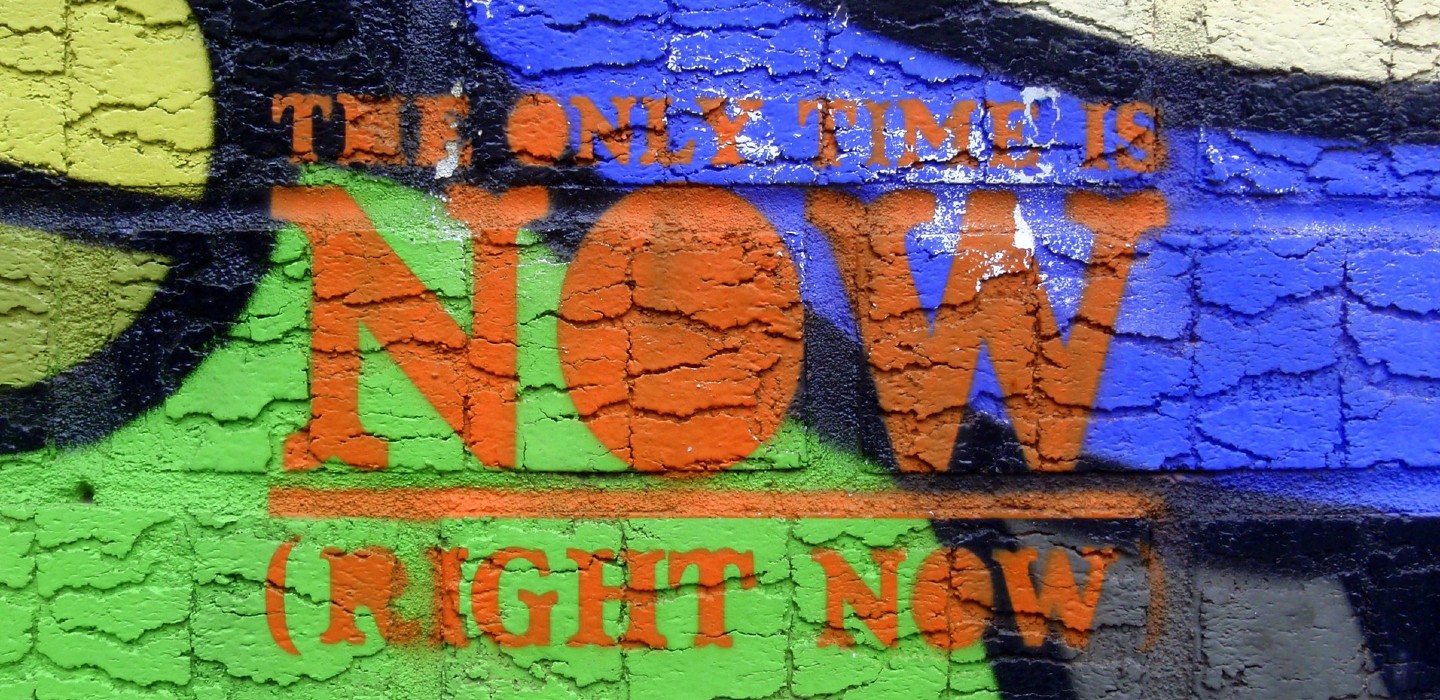 Graffiti Background with Orange words that say the only time is now