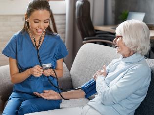 certified nursing assistant taking blood pressure on older woman