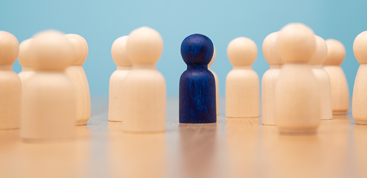 Wooden figure standing with team to show influence and empowerment