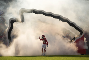 Kansas City Chiefs player wearing number 35 runs onto the field through a smoke-filled tunnel during pregame introductions at Arrowhead Stadium