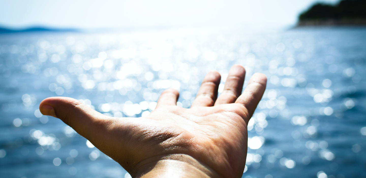 Hand reaching out over the water 