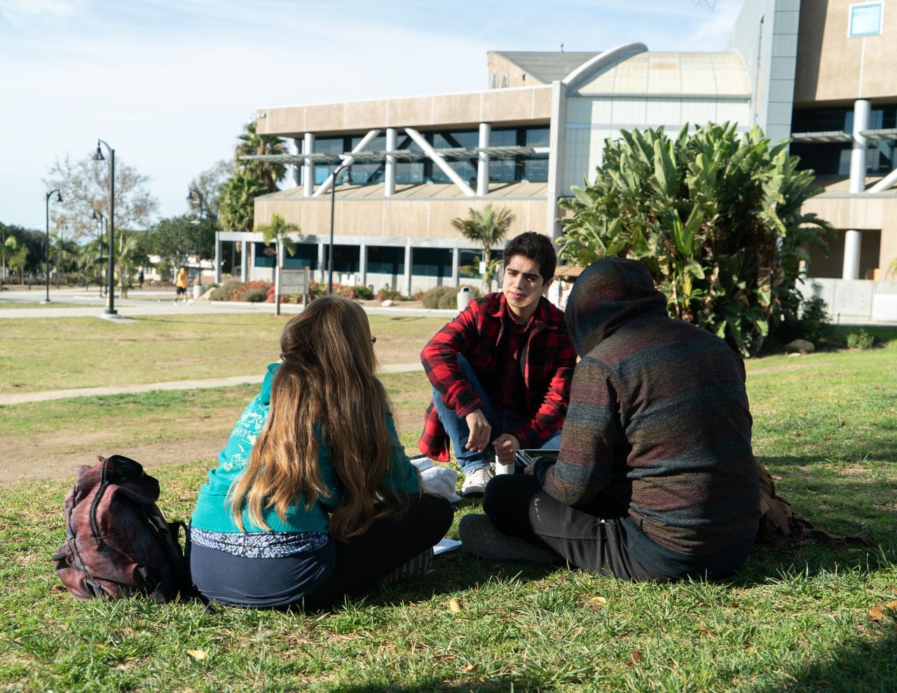 Three students sitting on the lawn