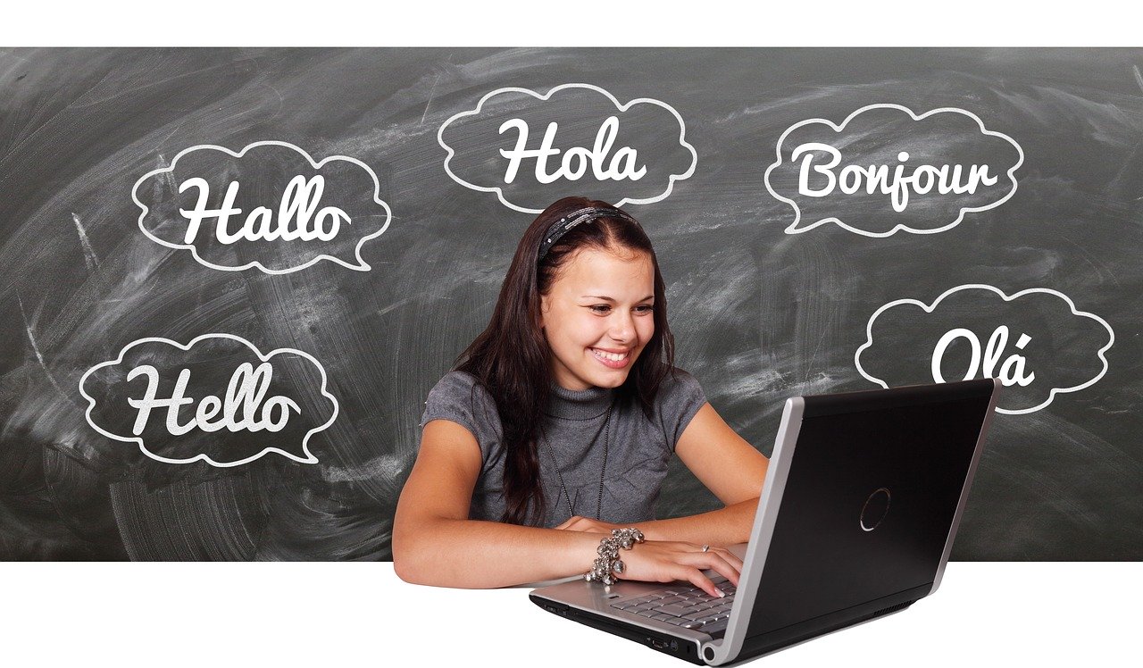 Woman looking at computer and behind her the words hello in different languages.