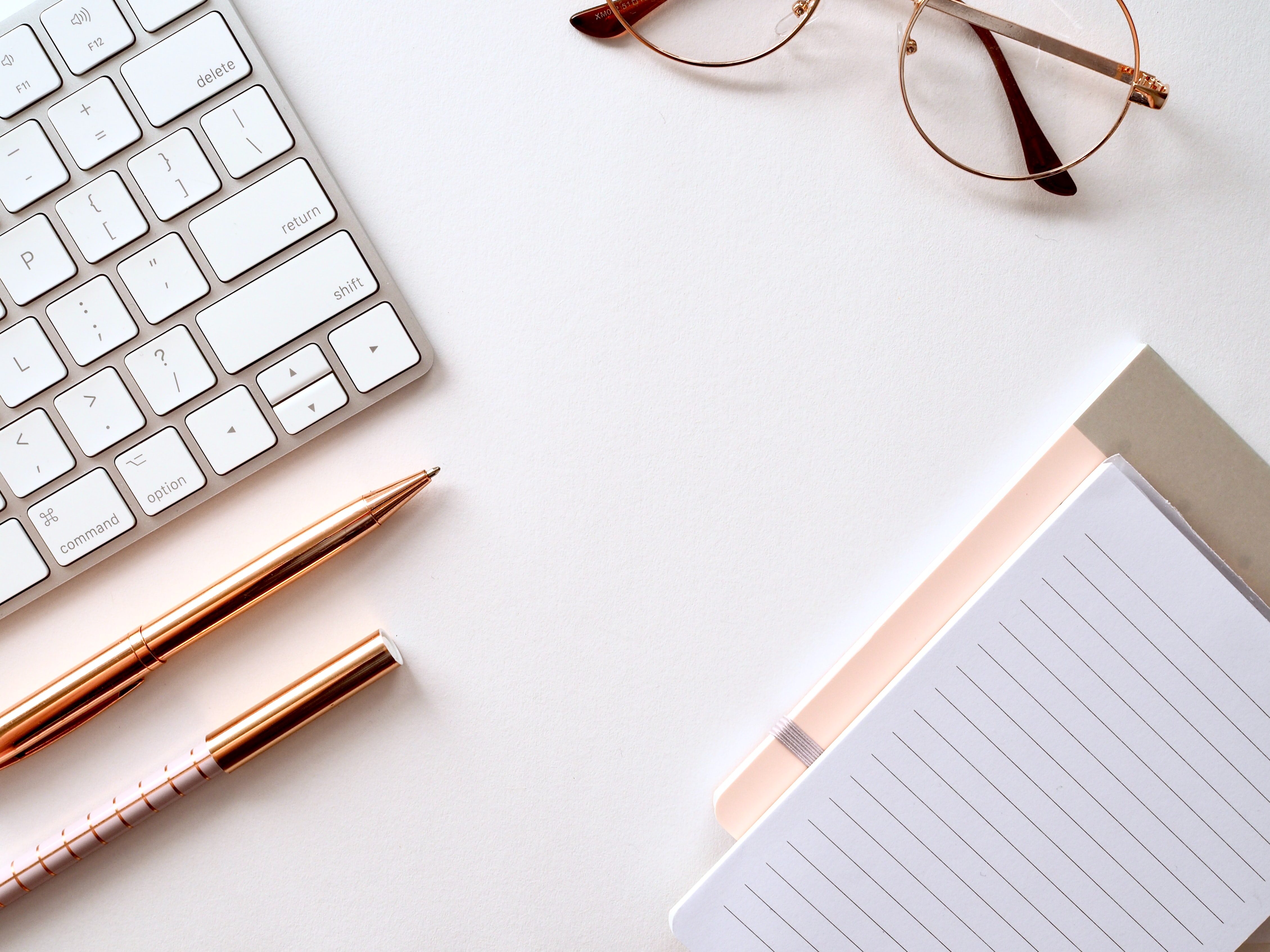 white background notebook, pencil, glasses, phone, and computer