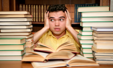 Student surrounded by textbooks, overwhelmed