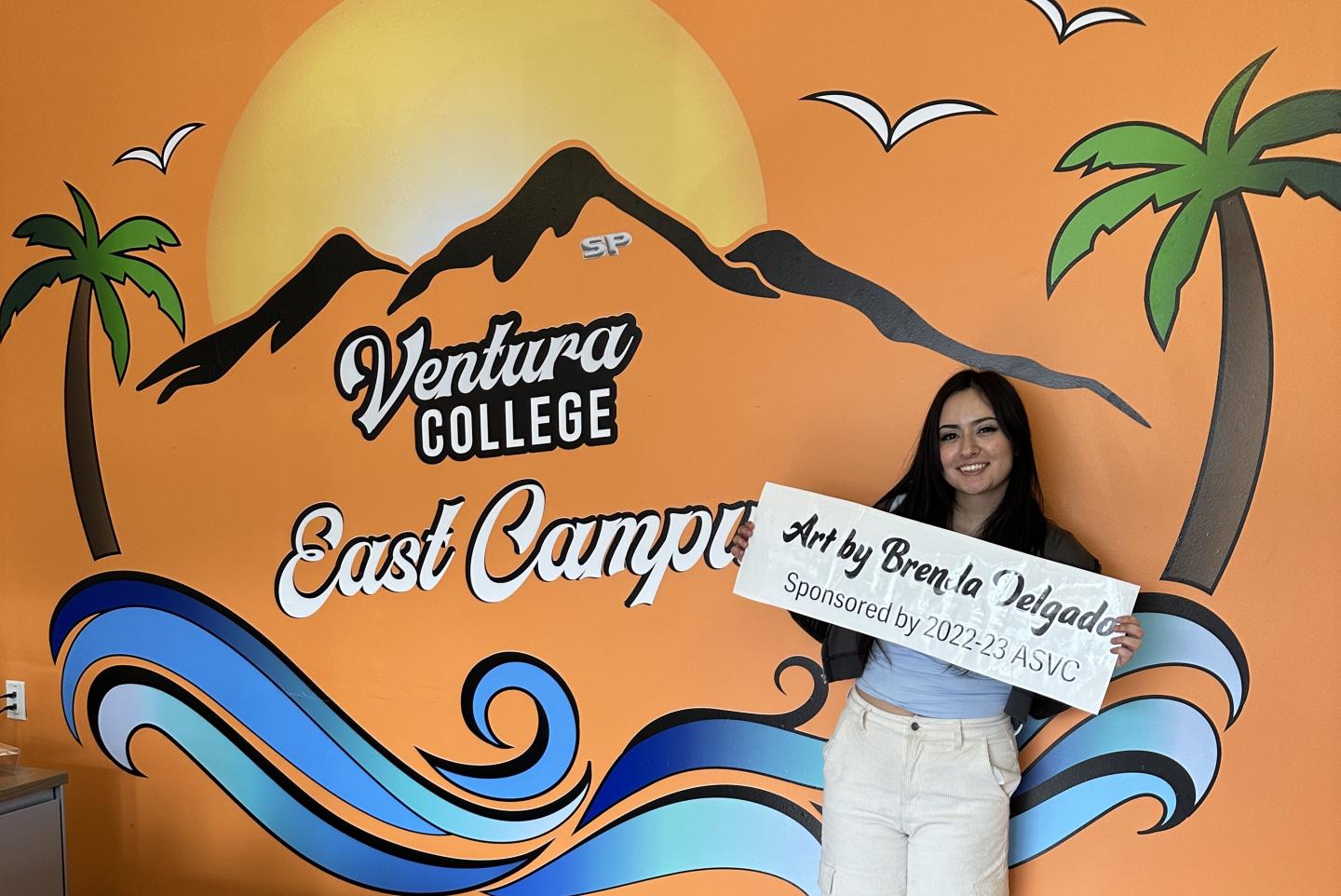 Brenda Delgado stands in front of VCEC Mural that she designed