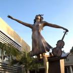 Bronze statue of a girl holding a violin.