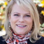 Kim Hoffmans, woman with blond hair smiling and wearing a red and white scarf