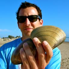 Nick holding clam shells on the beach