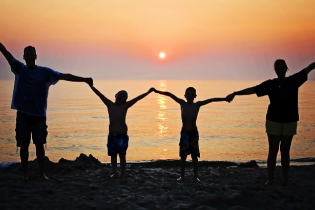 Silhouettes of a family of four at the beach while the sun is setting