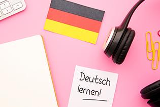 The words "Deutsch lernen!" on a post it note on top of a desk.