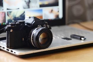 A digital camera sitting on top of a laptop.