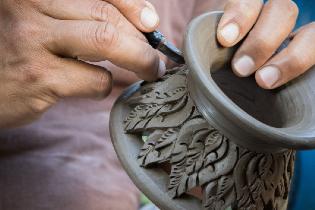 A person crafting a vase out of ceramics.