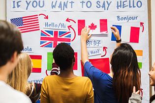 "If You Want to Say Hello" written on a white board with several country flags and language translations.