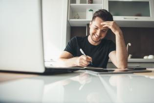 Young man working at laptop with pen.