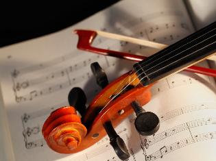 A violin and bow laying on a sheet of music.