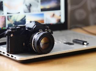 A digital camera sitting on top of a laptop.