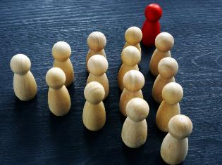 Wooden figure standing above a triangle of other figures to show influence and empowerment. concept of business leadership 