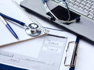 A stethoscope on top of documents and a laptop.