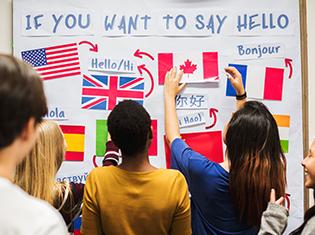 "If You Want to Say Hello" written on a white board with several country flags and language translations.