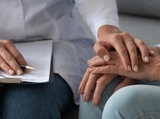 A person with a clip board holding another person's hands.