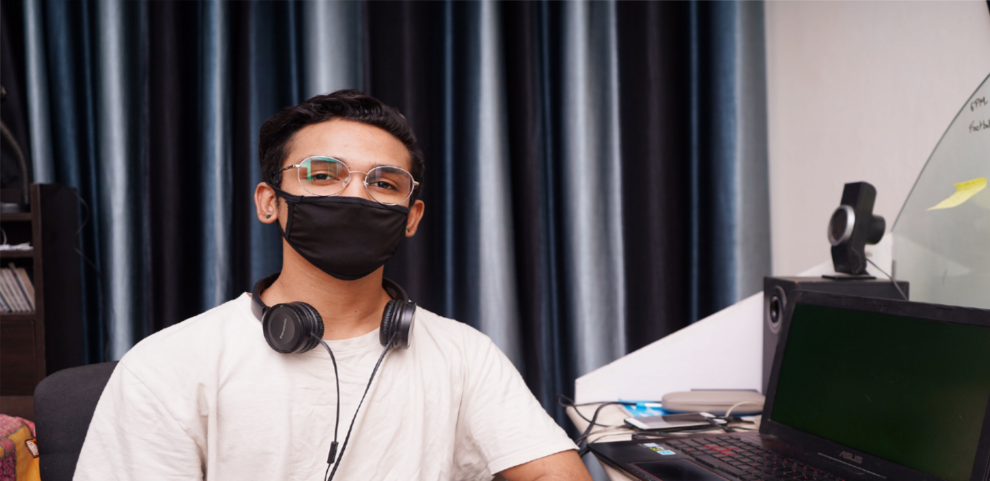student with facial covering at home on computer