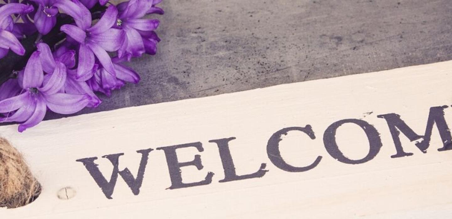Welcome plaque on the ground with purple flowers