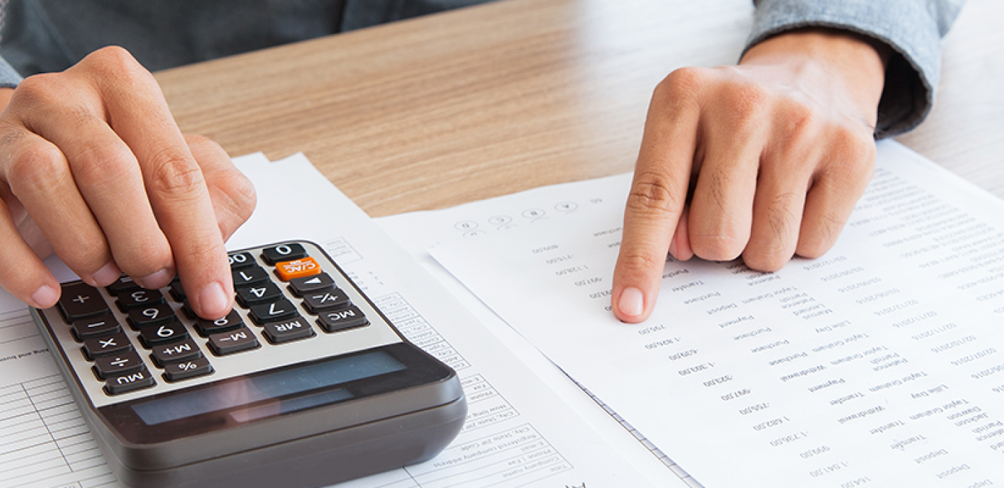 A person using a calculator while referencing financial documents.