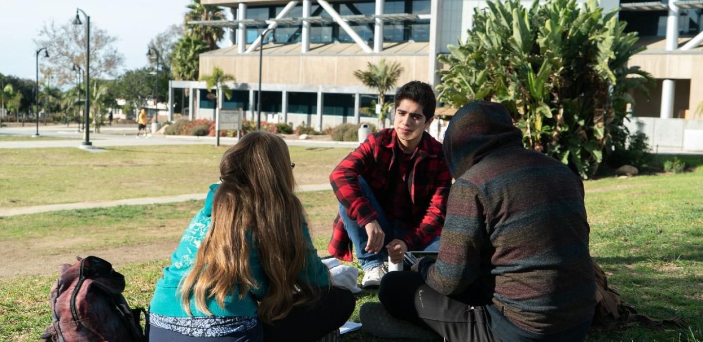 Three students sitting on the lawn