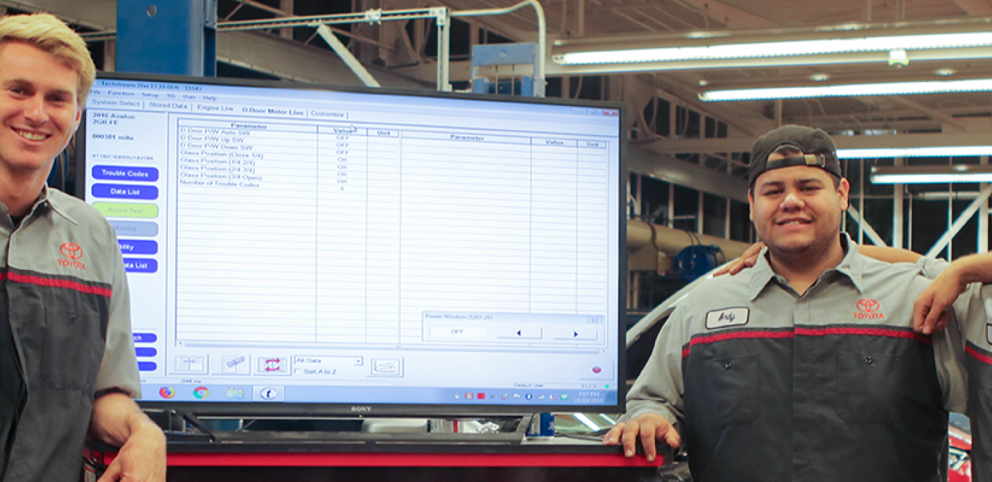 image of automotive students huddled around computer