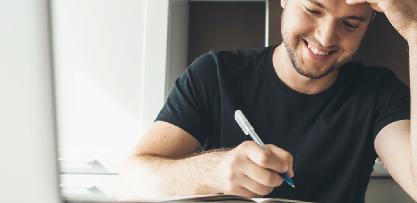 Young man working at laptop with pen. 