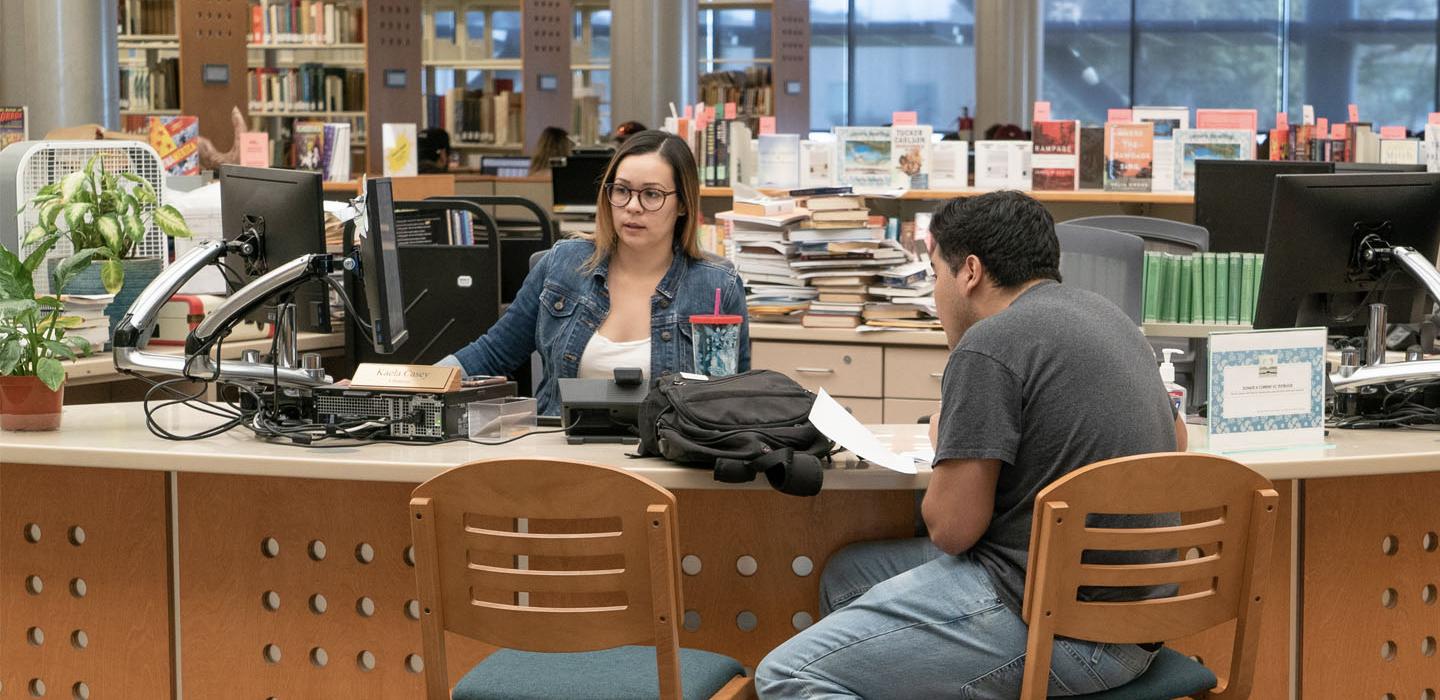 Librarian and student at the reference desk.