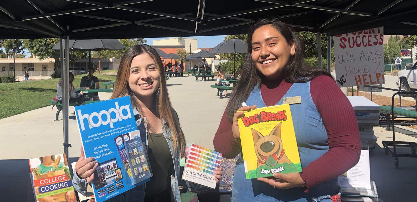 Students holding library books and flyers.