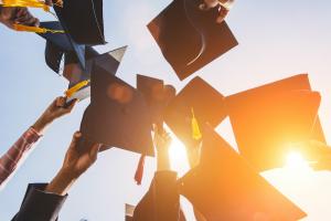 College graduates holding their caps and tassels in the air. College graduates holding their caps and tassels in the air.