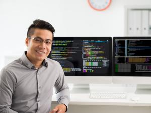 Male student is sitting at a computer with two large monitor Male student is sitting at a computer with two large monitor